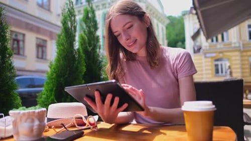 Young Woman Using Tablet Pc in a Cafe on a Summer Terrace
