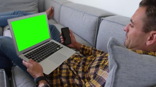 Man Relaxing on Sofa with Laptop and Phone