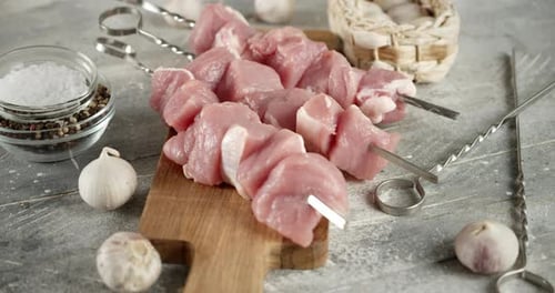Pork Raw Kebab on Skewers Slowly Rotates on the Table.