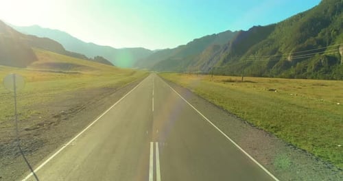 Aerial Low Air Flight Over Mountain Road and Meadow at Sunny Summer Morning