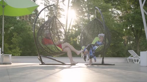 Couple d'âge mûr assis sur une chaise suspendue au coucher du soleil