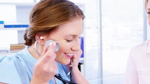 Friendly Nurse Listens to Patient Heartbeat with Stethoscope