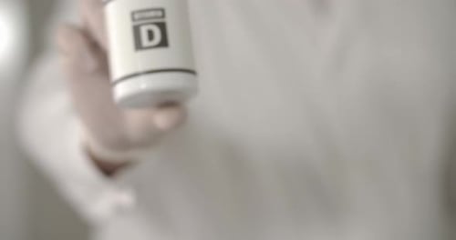 Hand Holds White Bottle of Vitamin D