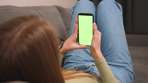 Woman sitting on a couch with Green Screen Smartphone