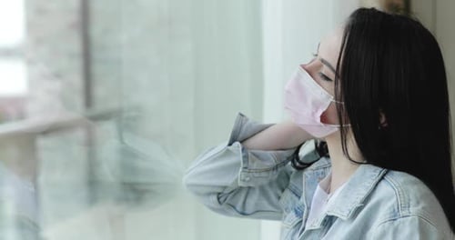 Confused Girl in Mask From Virus Comes to Glass Door Leans Looks and Nervous