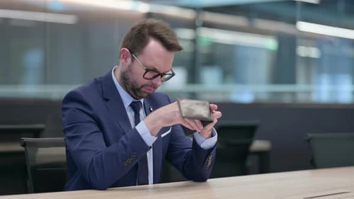 Geschäftsmann mittleren Alters checkt leere Brieftasche im Büro