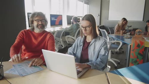 Senior Businessman Working with Young Female Colleague in Office