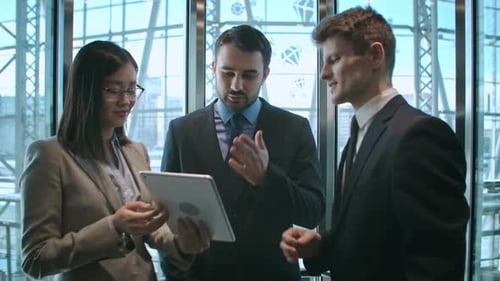 Business Colleagues Discussing on Tablet in Elevator
