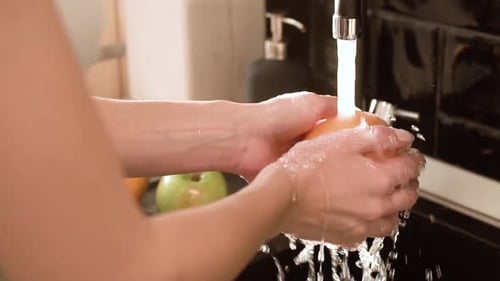 Woman Washing Orange in Modern Kitchen Sink
