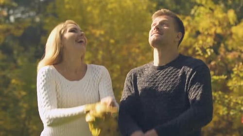 Romantic Couple Playfully Throwing Autumn Leaves in Park