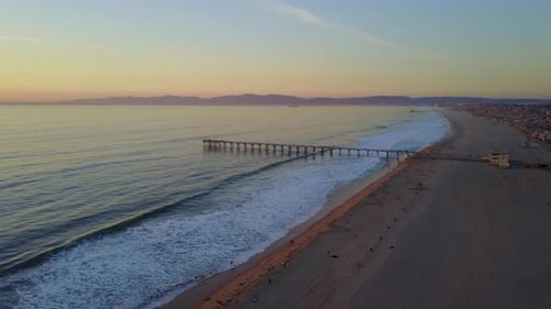 Aerial drone uav view of a pier at sunset at the beach and ocean.