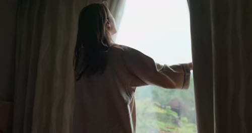 Woman Opens Curtains to Mountain View in Hotel