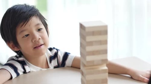 Süßes asiatisches Kind, das Holzklötze-Stapelspiel spielt