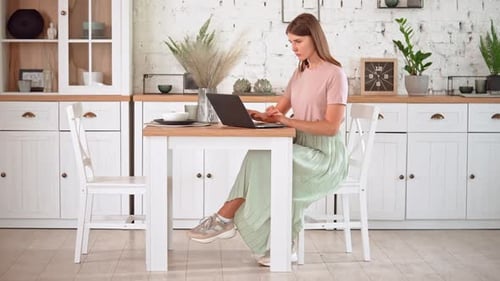 Woman Working on Laptop in Bright Kitchen