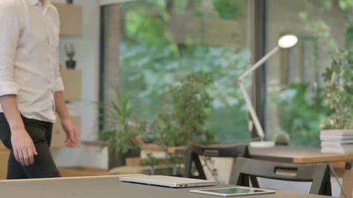 Young Man Coming and Opening Laptop Starting Work in Modern Office