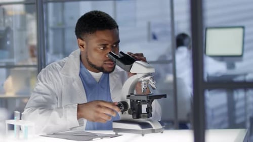 Afroamerikanischer Techniker arbeitet im Labor mit Mikroskop
