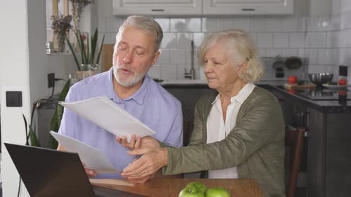 Senior Couple Reviews Paperwork Together at Home