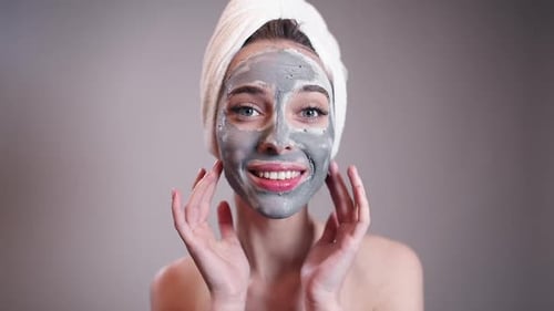 Woman Applies Facial Mask with Towel on Head