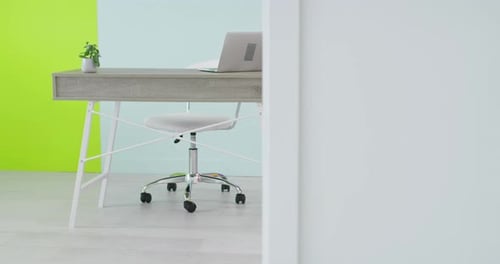 Desk with Laptop Computer Standing in Home Office in Front of an Empty Wall
