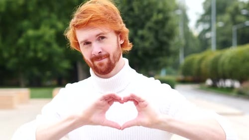 Smiling Man Makes Heart Shape with Hands
