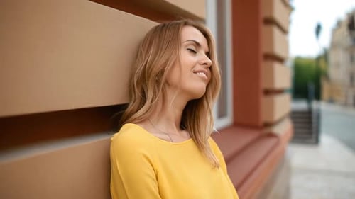 Attractive Blonde Woman Leaning Against Building Smiling