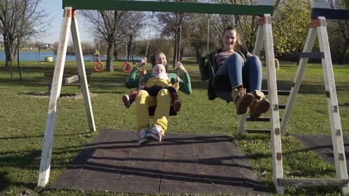 Family playing at swing in public playground, Zagreb, Croatia.