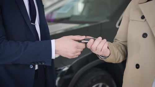 An Unrecognizable Manager Shakes Hands with a Client and Hands Over the Car Key