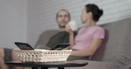 Couple Relaxing on Couch With Phones Nearby