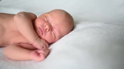 Infant Sleeping Peacefully on a Soft White Blanket