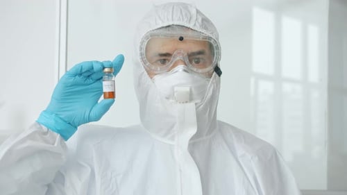 Researcher in Hazmat Suit Holding Vaccine Vial