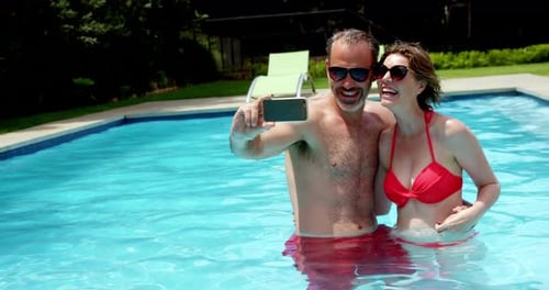 Couple taking a selfie on mobile phone in swimming pool