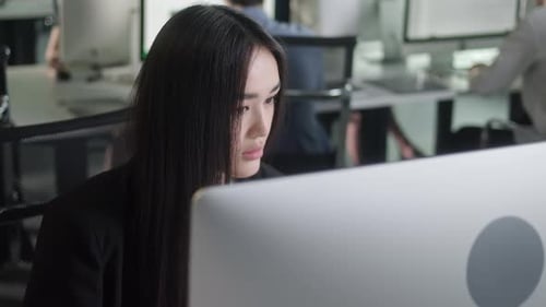 Attractive Young Woman Working on Decktop Computer While Working in Big Open Space Office