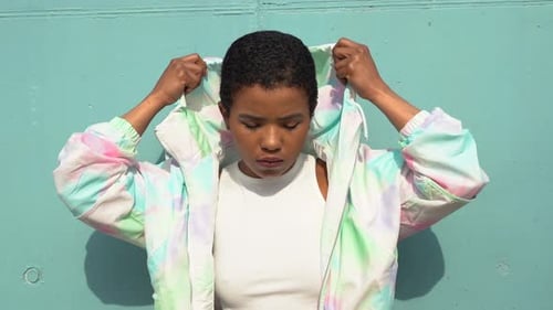 Pretty woman posing in front of blue wall, wearing hood