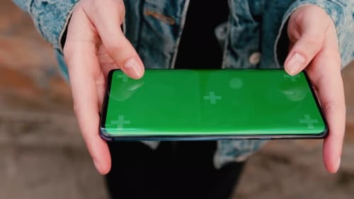 Woman Uses a Phone with a Green Screen Layout a Color Key Watching Content Videos Photos Playing a