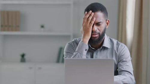 Man With Laptop Looking Concerned and Frustrated