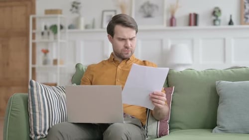 Man works from home on laptop and documents