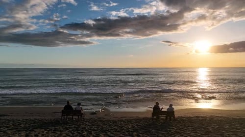 People sit on the beach and watch the sunset