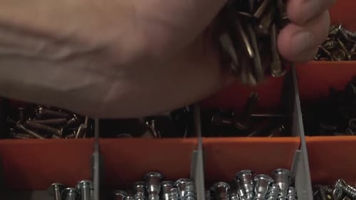 Le maître qui produit et installe des meubles verse de nombreux boulons dans la cellule de la valise. Gros plan