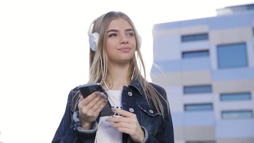 Beautiful Woman In Headphones Listening Music On Phone Outdoors