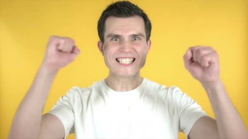Man Celebrating Success with Fist Pump on Yellow