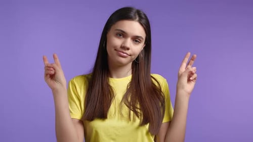 Pretty Woman Showing with Hands and Two Fingers Air Quotes Gesture Bend Fingers Isolated Over Violet