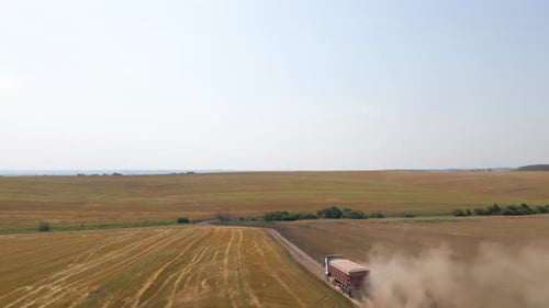 Aerial View of Cargo Truck Driving on Dirt Road Between Agricultural Wheat Fields Making Lot of Dust