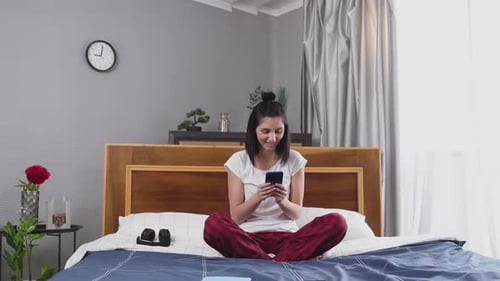 Woman Using Smartphone on Bed at Home