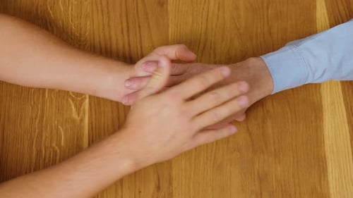 Young Adult Holding Senior Adult Hand on Table