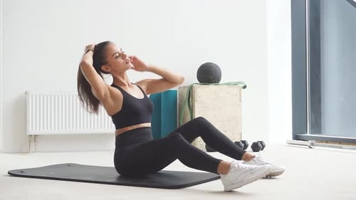 Slim Woman in Sportswear Sitting on the Floor Preparing for Classes