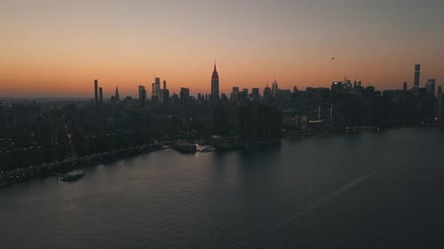 AERIAL: Over East River Overlooking Manhattan New York City Skyline in Beautiful Dawn Sunset Orange