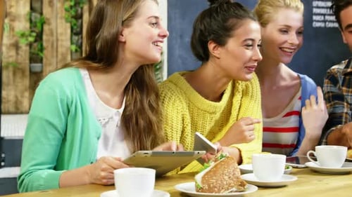 Friends laughing at a cafe using a laptop