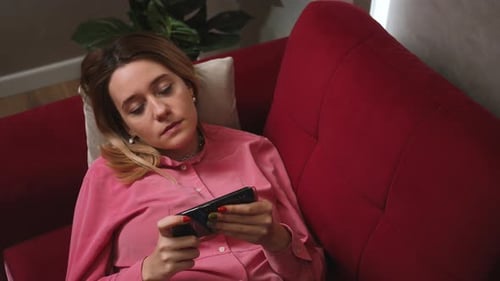 Close Up Relaxed Woman Hold Use Smartphone Watching Social Media on the Couch Sofa at Home