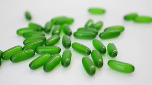 Rotating shot of green capsules on a white table