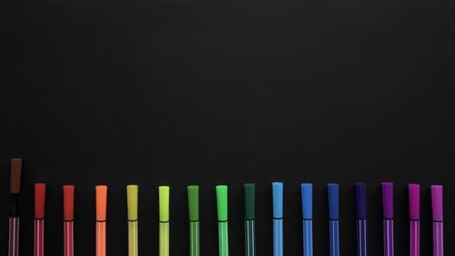School Markers of Different Colors Are Located on the Black Surface. Stop Motion Animation with